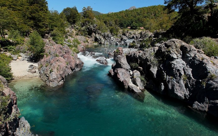 Turquoise river flowing through rocky terrain with lush green forest