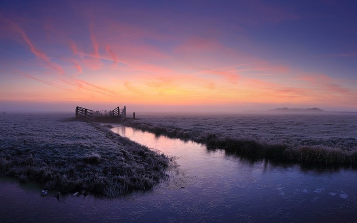 Frosty field with a canal at sunrise