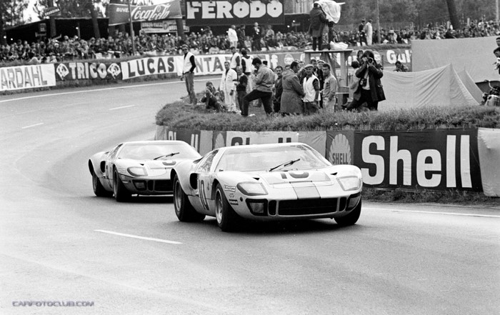 Ford GT40 race cars on a track with spectators