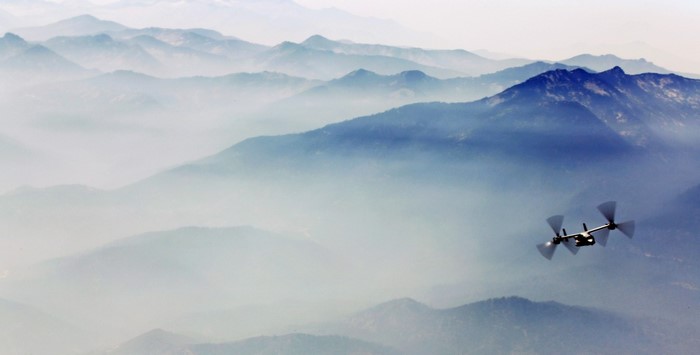 V-22 Osprey flying over misty mountains
