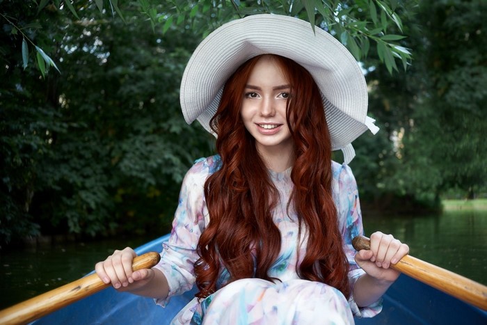 Redhead woman in a hat rowing a boat