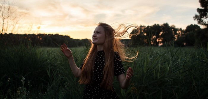 Young woman with red hair in a field at sunset