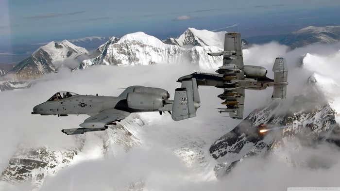 Two A-10 Thunderbolt II aircraft flying over snowy mountains