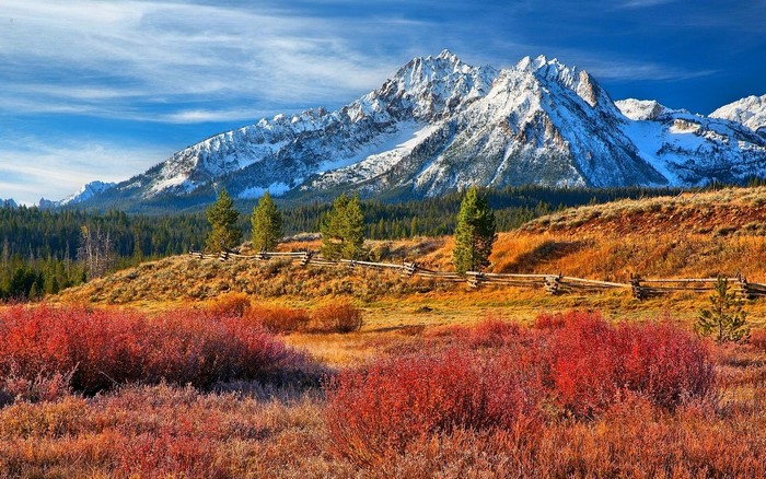 Autumn landscape with snow-capped mountains and a wooden fence