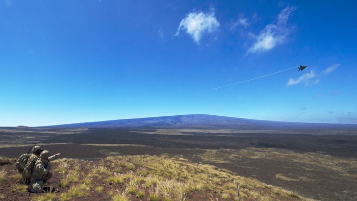 Military aircraft flying over a volcanic landscape with soldiers