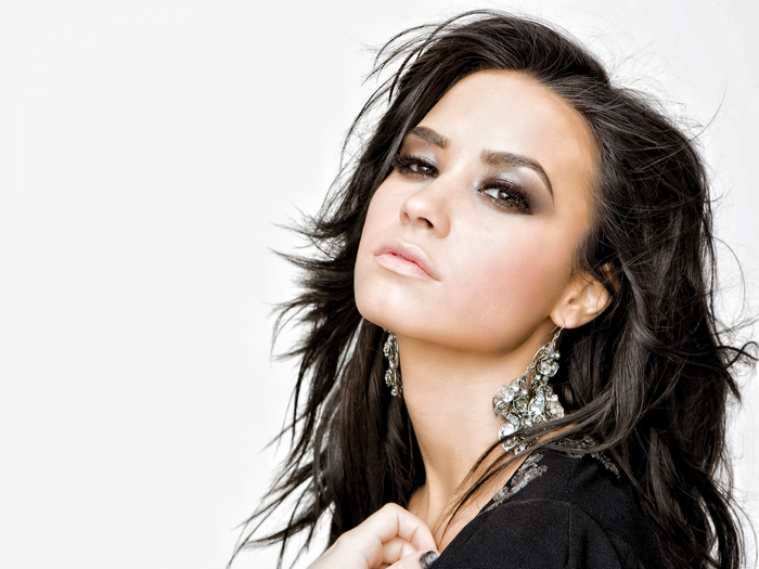 Demi Lovato portrait with long dark hair and large earrings