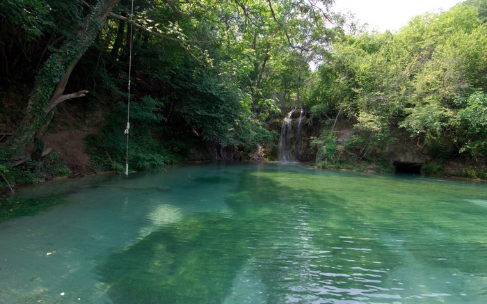 Turquoise pool with waterfall and rope swing