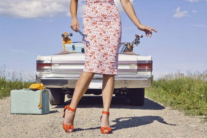 Woman with wrench and luggage by car