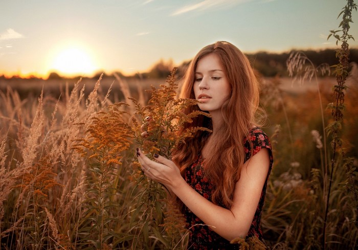 Woman with red hair in a field at sunset