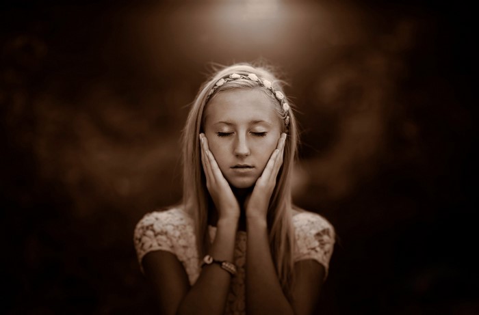 Young woman with eyes closed and hands on face