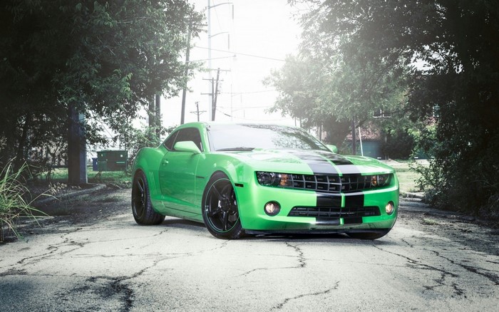 Green Chevrolet Camaro with black stripes on a cracked road