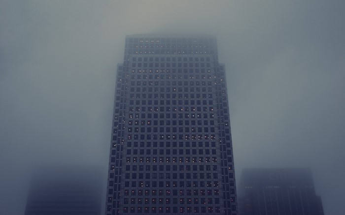 Skyscraper in fog with lights on