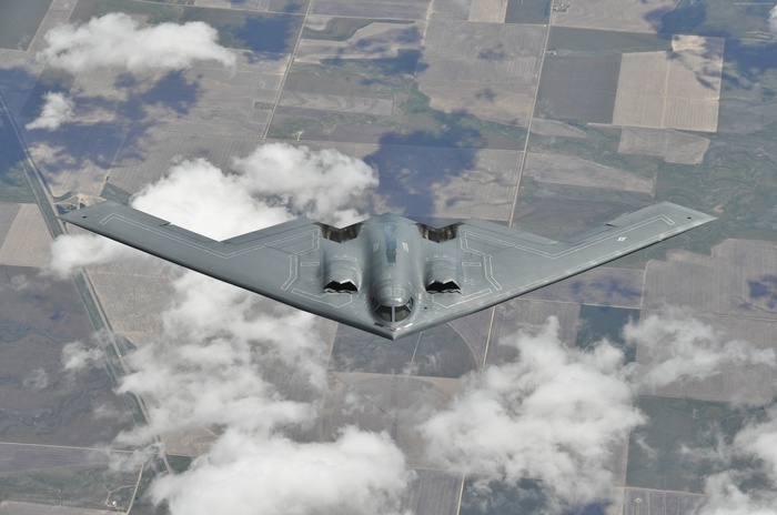 Northrop B-2 Spirit bomber flying over farmland