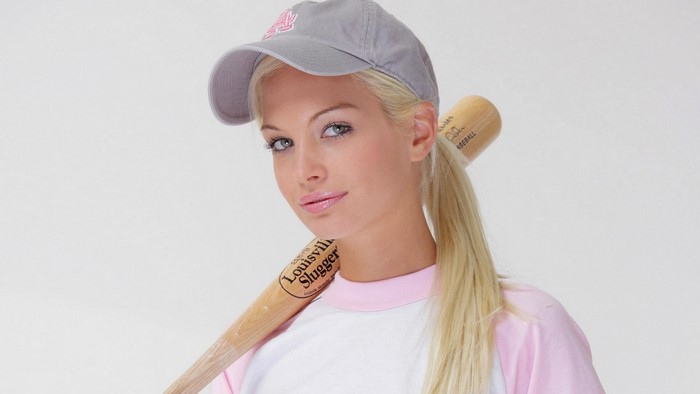 Woman wearing a baseball cap and holding a baseball bat