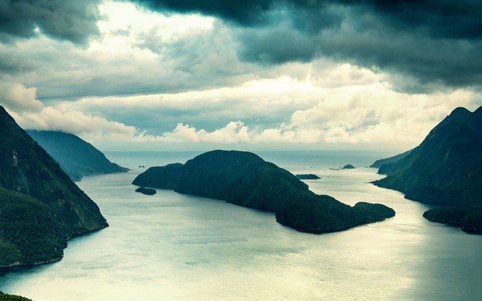 Overcast sky over a fjord with green mountains and sea