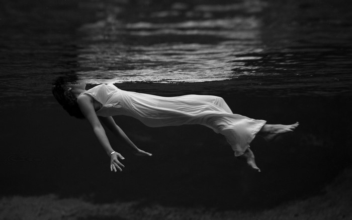 Woman in white dress floating underwater