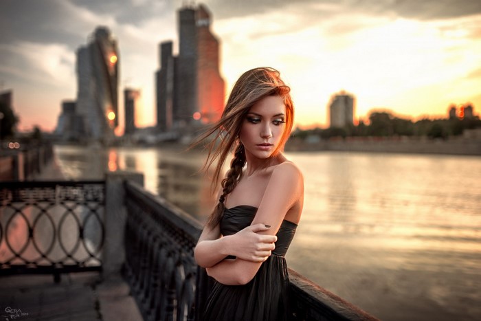 Woman in black dress by river at sunset