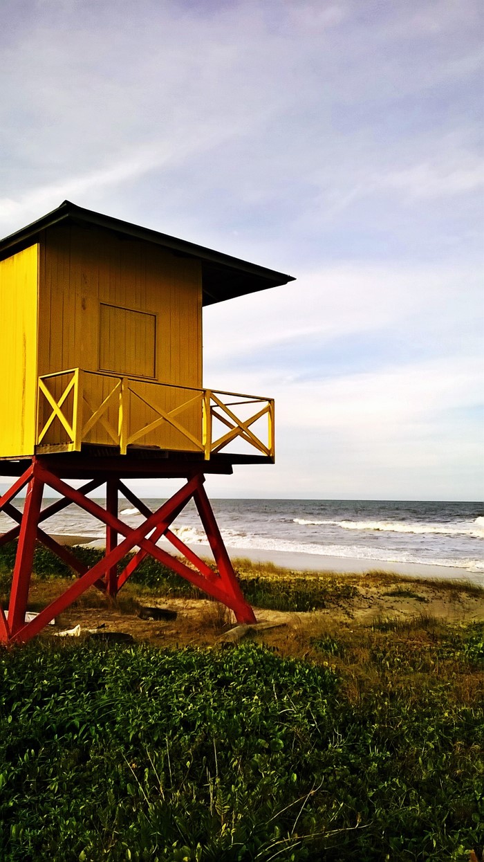 Yellow lifeguard tower on a beach with ocean waves