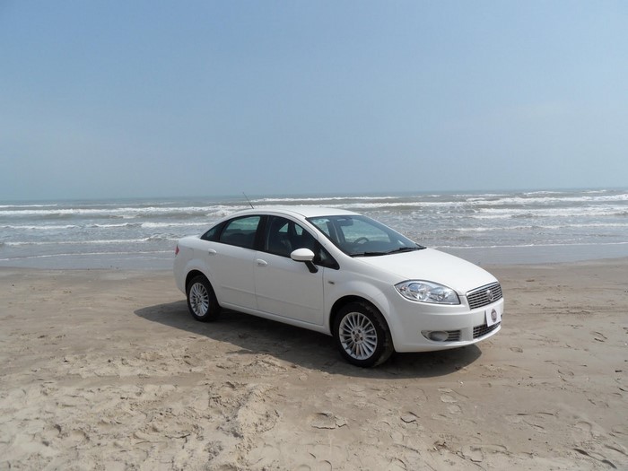 White Fiat Linea sedan on a sandy beach