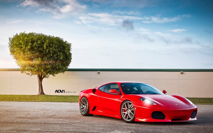 Red Ferrari F430 parked near a tree