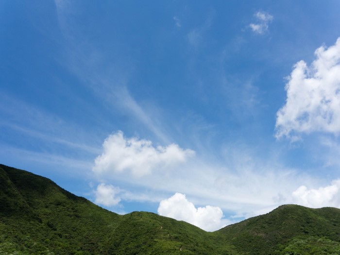 Green mountains under a blue sky with clouds
