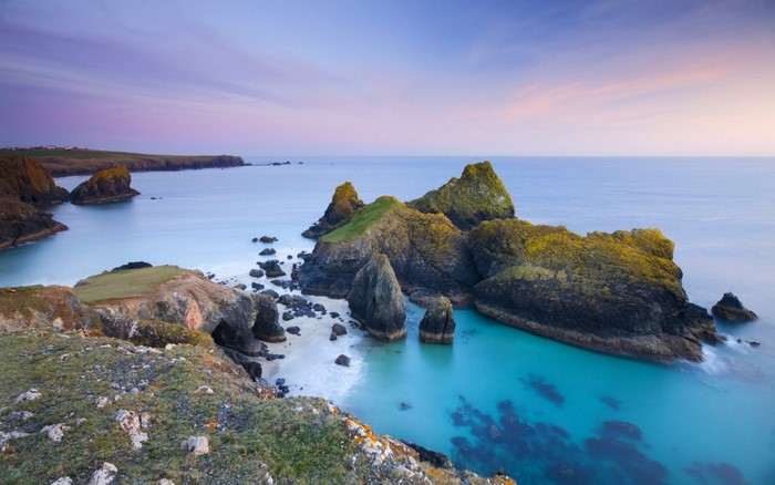 Rocky coast with turquoise water and purple sky