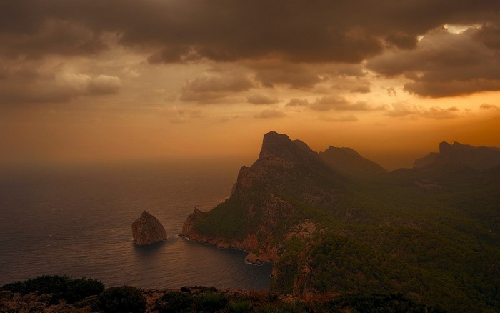 Rocky coast with mountains at sunset