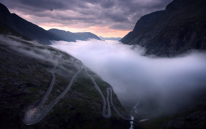 Winding mountain road through fog and clouds in Norway