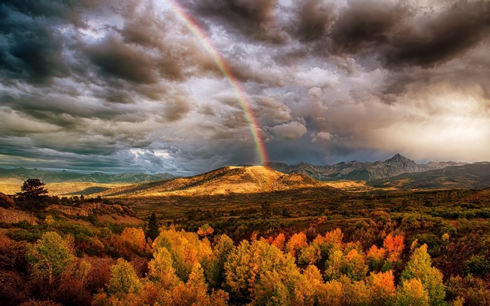 Rainbow over autumn mountains at sunset