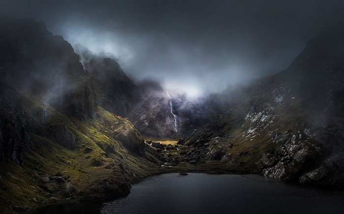 Misty mountain valley with a lake and waterfall