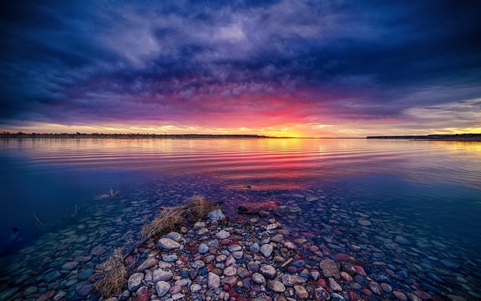 Sunset over a calm lake with rocky shore