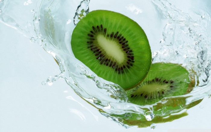 Two kiwi slices splashing in water