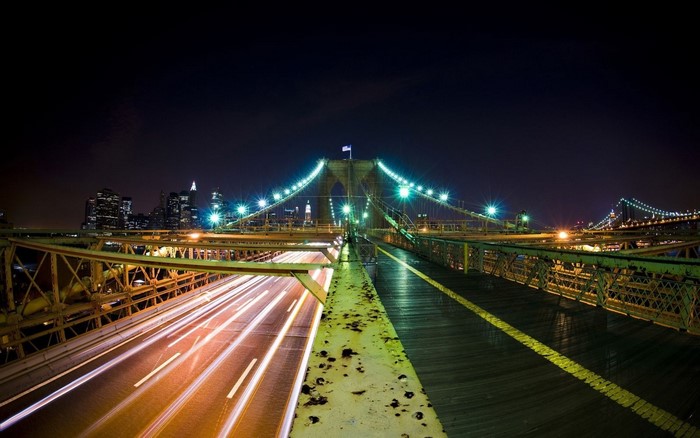 Brooklyn Bridge at night with light trails and New York City skyline