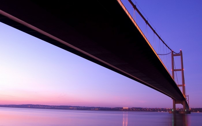Suspension bridge over a river at dusk