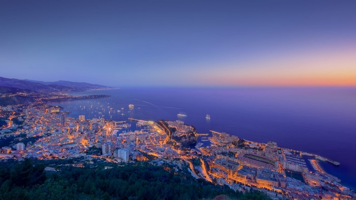 Cityscape of Monaco at dusk with boats in the harbor