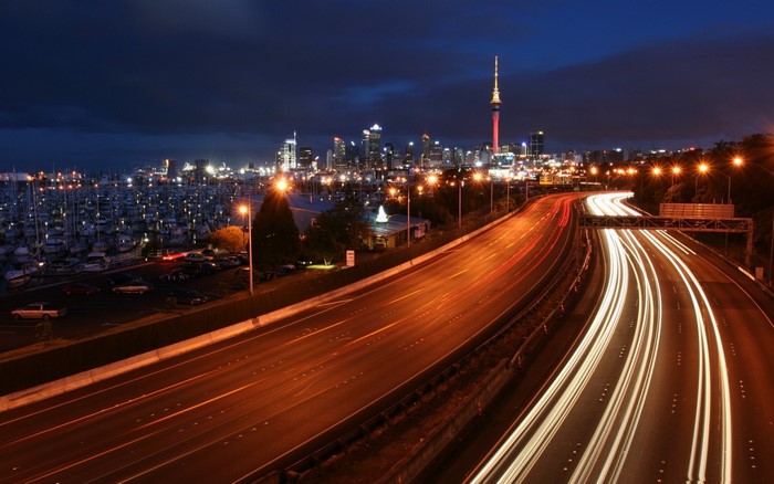 Auckland skyline with Sky Tower and light trails on highway at night