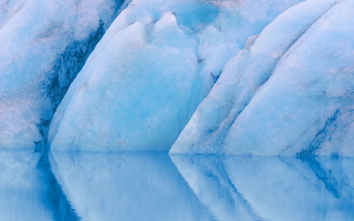 Blue ice formations reflected in calm water