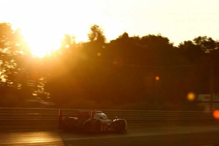 Race car speeding on a track at sunset