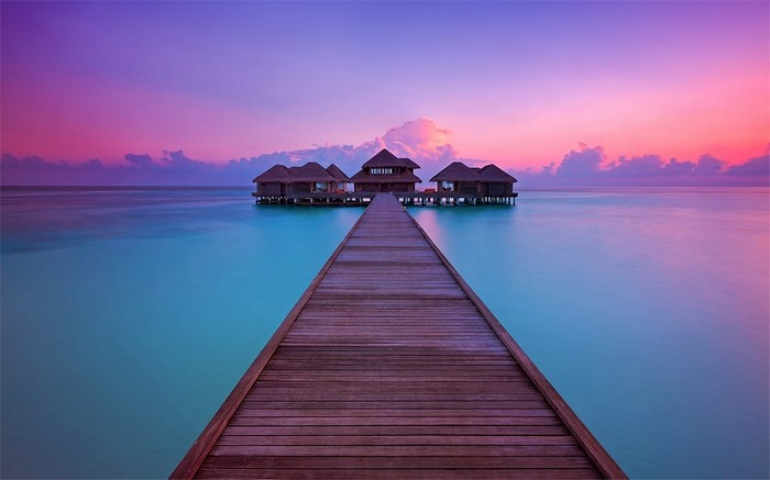 Overwater bungalows at sunset with wooden walkway