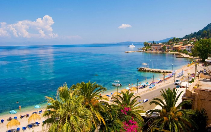 Coastal town with beach, palm trees, and turquoise sea