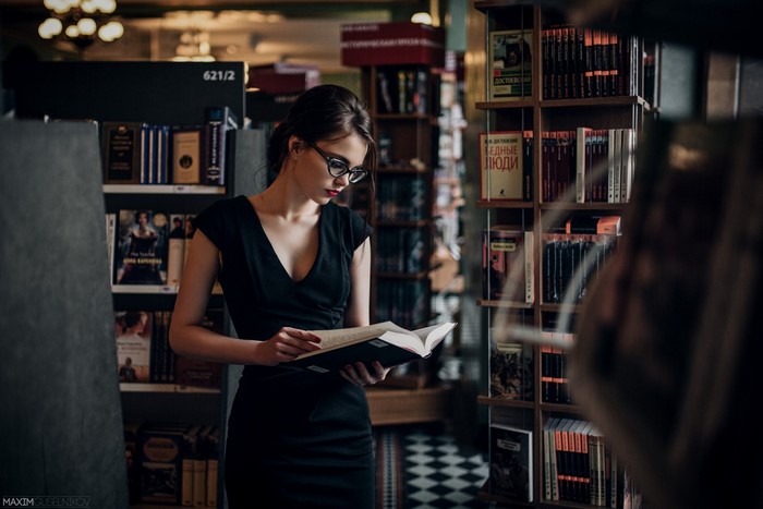 Woman in black dress reading a book in a library