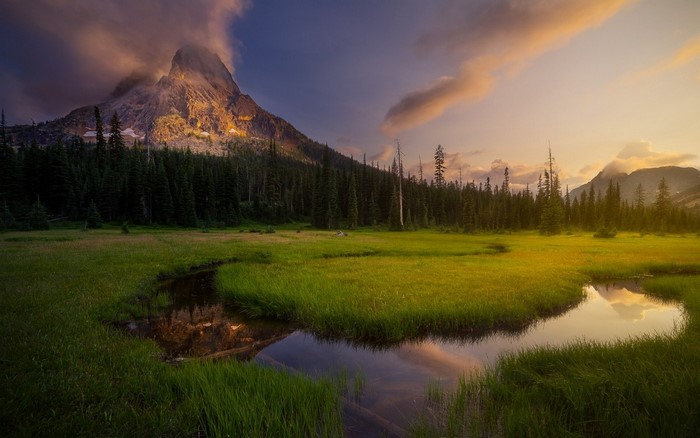 Mountain peak at sunset with a stream in a meadow