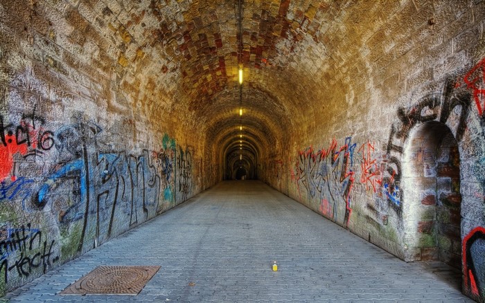 Graffiti-covered tunnel with lights and brick walls