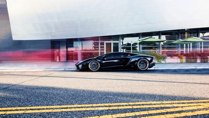 Black Lamborghini Aventador parked by modern building