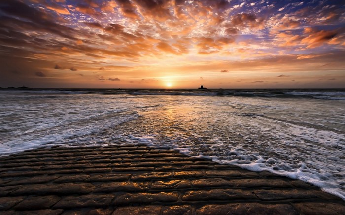 Sunset over the ocean with rocky shore
