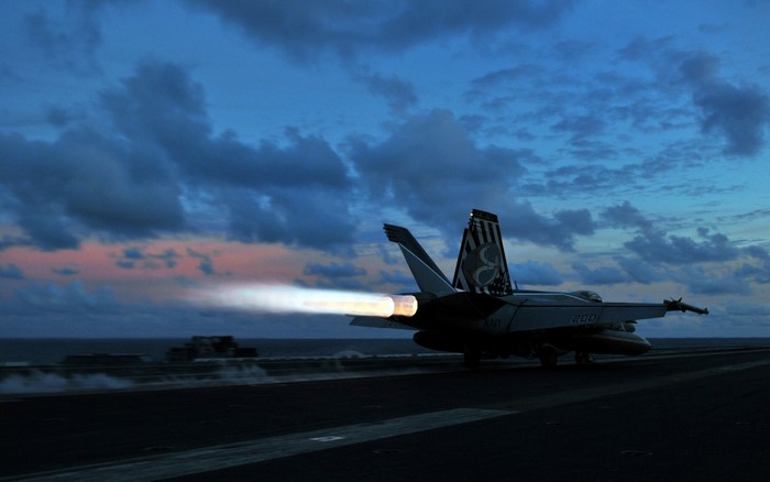 F/A-18 Hornet taking off from aircraft carrier at dusk