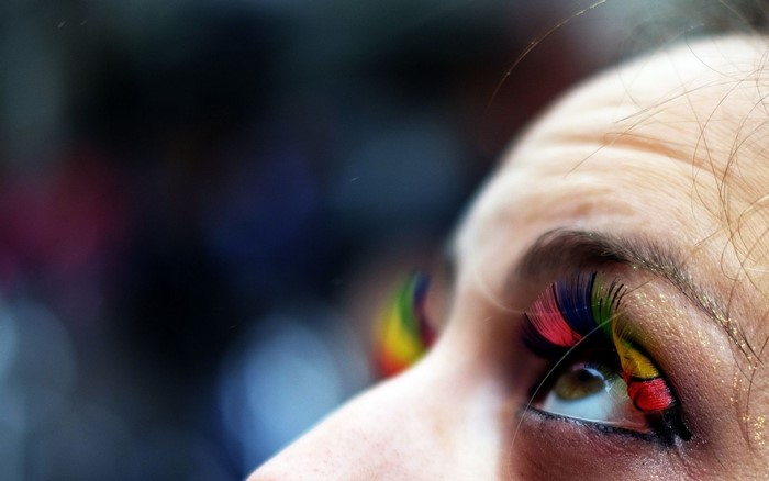 Close-up of a person's eye with rainbow-colored eyelashes