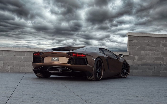 Brown Lamborghini Aventador parked near a brick wall