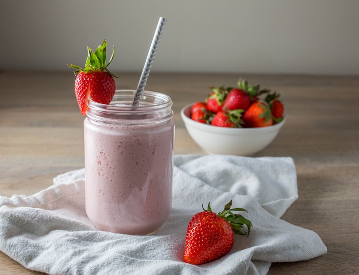 Strawberry smoothie in a mason jar with fresh strawberries