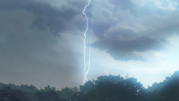 Lightning strike over trees under stormy clouds